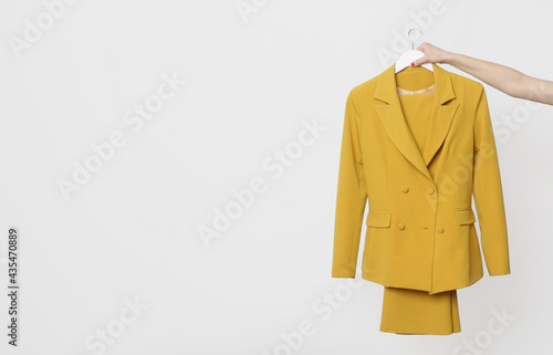 Yellow double-breasted blazer hanging on a coathanger isolated on white background. Modern premium quality hand made woman's fashion. 