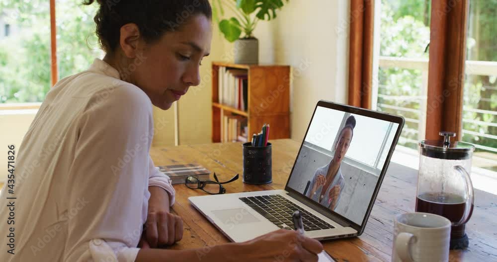 African american woman taking notes while having a video call on laptop at home African american woman taking notes while having a video call on laptop at home