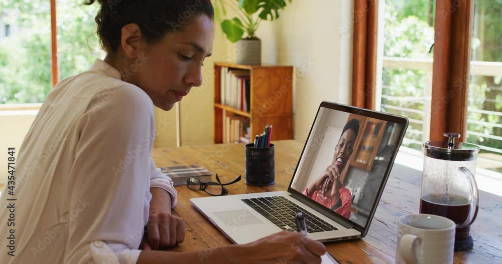 African american woman taking notes while having a video call on laptop at home African american woman taking notes while having a video call on laptop at home
