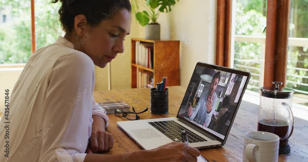 African american woman taking notes while having a video call on laptop at home African american woman taking notes while having a video call on laptop at home