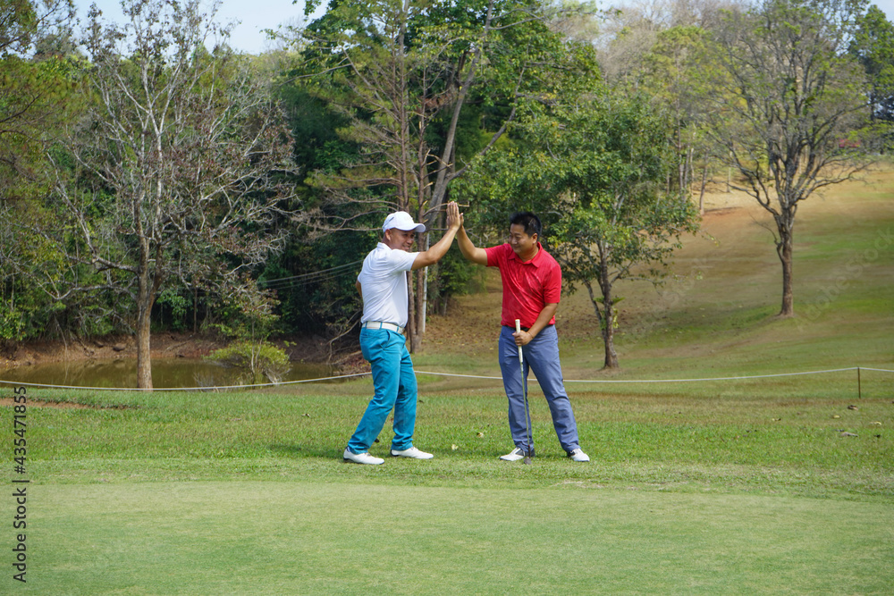 Obraz premium Shot of two golfers congratulating each other with a high five after a game of golf.