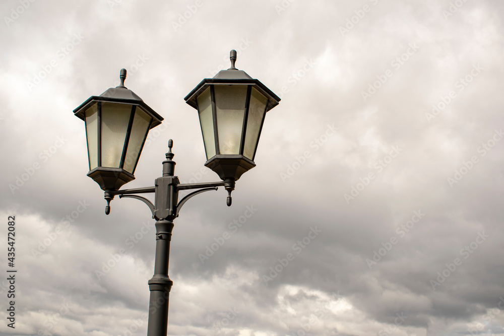 Vintage street dual lights on a cloudy sky background.