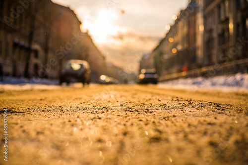 Bright winter sun in a big city, on the snowy street going cars. View from the road level