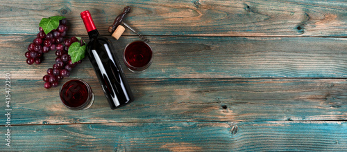 Red wine background with bottle, glasses, grapes and vintage corkscrew on faded blue wood