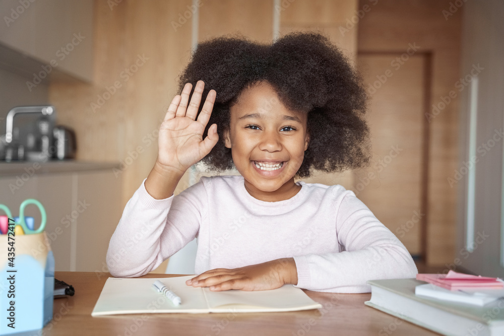 Happy mixed-race preteen girl school pupil raising hand on online lesson Happy mixed-race preteen girl school pupil raising hand on online lesson