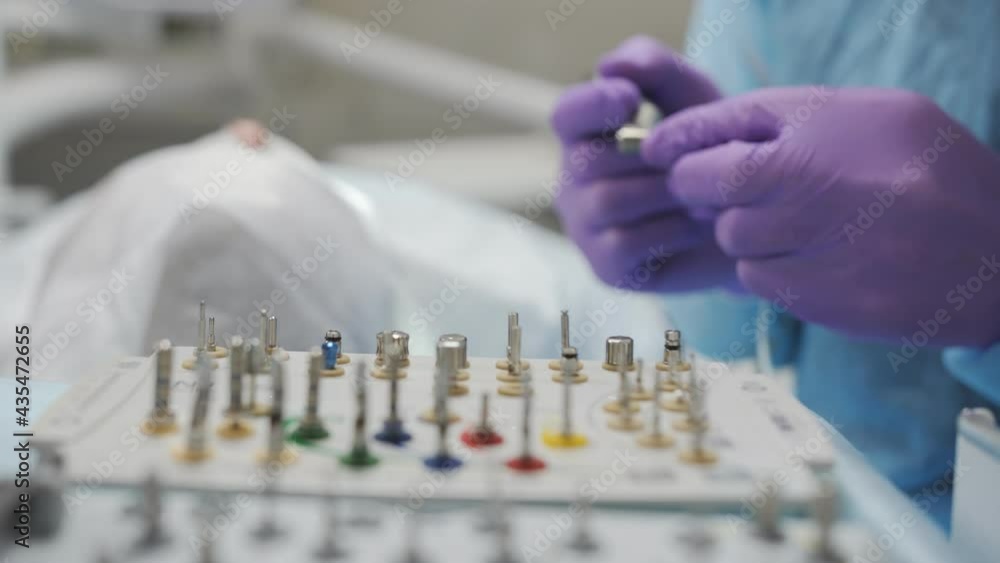 The dental surgeon prepares the instruments for the implantation of the tooth. Dental surgical instruments before implantation on assistant table in modern clinic. The dental surgeon prepares the instruments for the implantation of the tooth. Dental surgical instruments before implantation on assistant table in modern clinic.