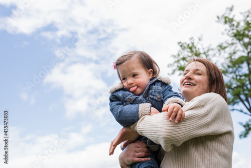 low angle view of happy woman holding disabled kid in park