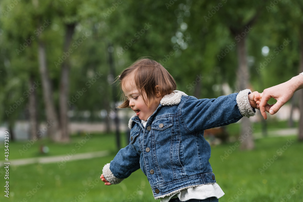 disabled child in denim jacket holding hand of mother in park disabled child in denim jacket holding hand of mother in park