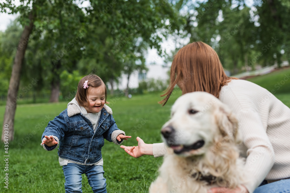 woman with outstretched hand near autistic kid and blurred dog in park
