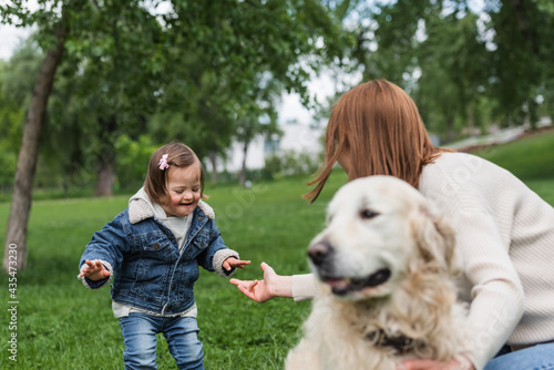woman with outstretched hand near autistic kid and blurred dog in park