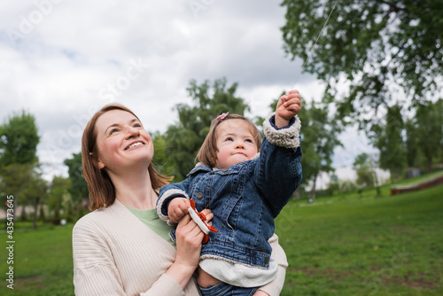 happy mother and disabled kid with autism looking at sky