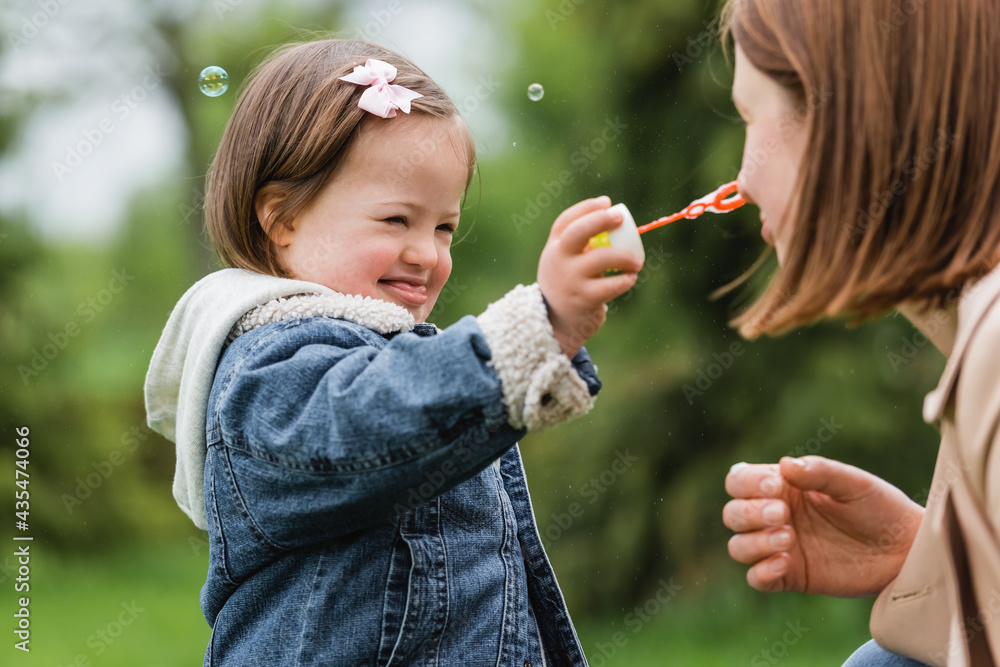 autistic child holding bubble wand near face of mother in park autistic child holding bubble wand near face of mother in park
