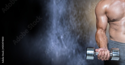 Composition of muscular man exercising with dumbbells over black and white blur