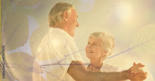 Composition of senior couple dancing, smiling and autumn foliage