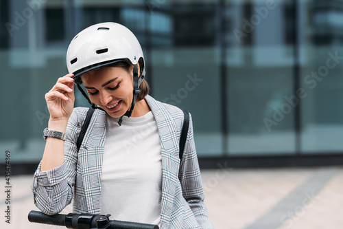 Portrait of a beautiful young woman with safety helmet looking down standing outdoors at office building