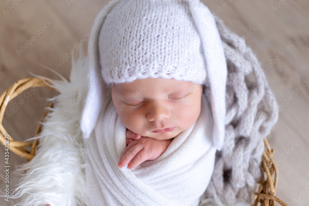 a newborn baby sleeps sweetly in a diaper-cocoon in a hat with hare ears, portrait a newborn baby sleeps sweetly in a diaper-cocoon in a hat with hare ears, portrait