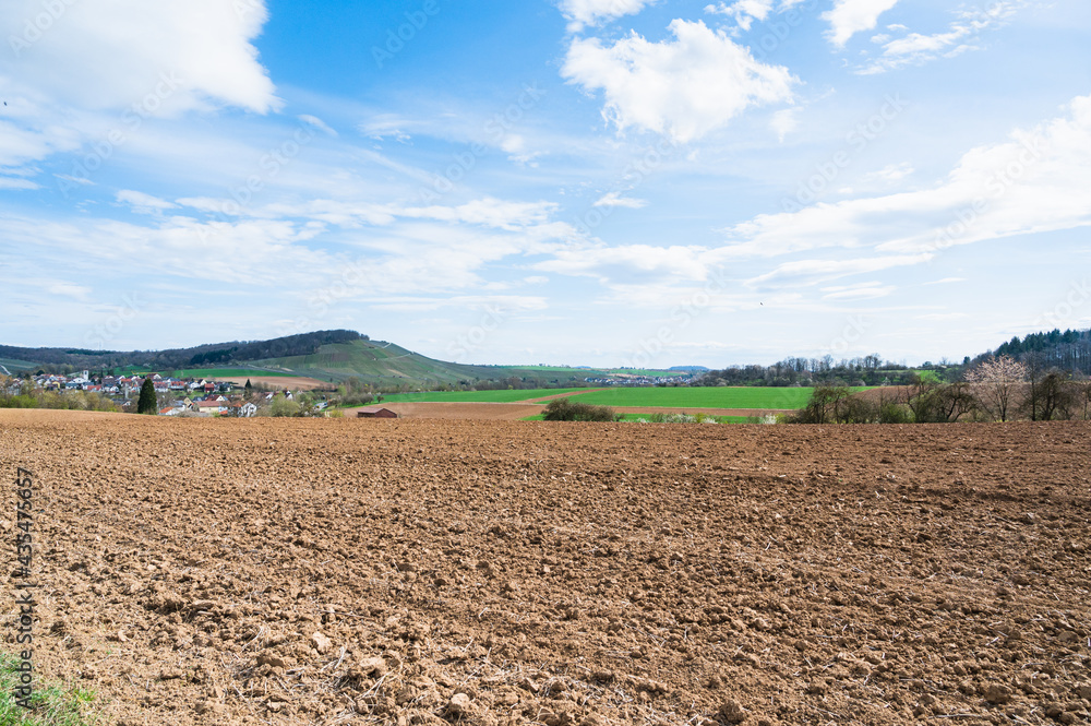 A large agricultural field near a village under a bright sky A large agricultural field near a village under a bright sky