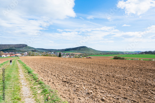A large agricultural field near a village under a bright sky