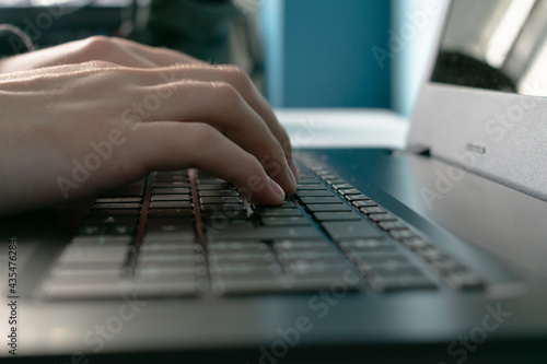 Close-up of unrecognizable person typing on a laptop.