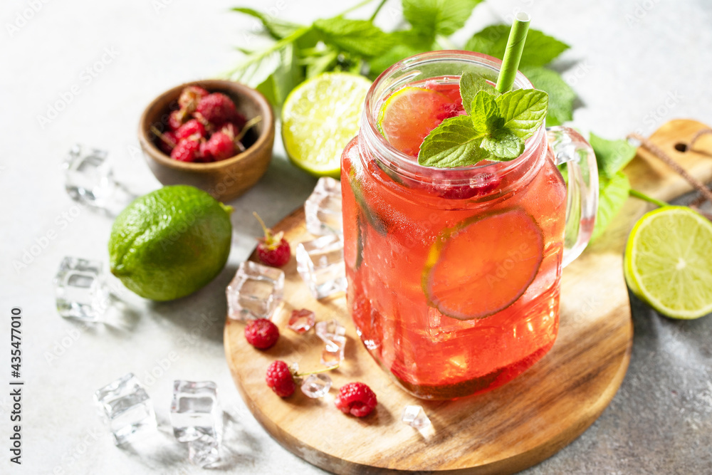Soft drinks, healthy beverage. Refreshing summer glasses drink raspberry with mint lime and ice on a stone table. Soft drinks, healthy beverage. Refreshing summer glasses drink raspberry with mint lime and ice on a stone table.