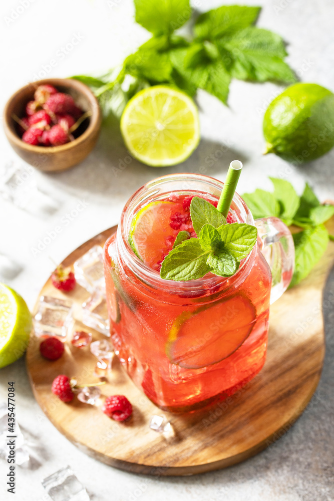 Soft drinks, healthy beverage. Refreshing summer glasses drink raspberry with mint lime and ice on a stone table. Soft drinks, healthy beverage. Refreshing summer glasses drink raspberry with mint lime and ice on a stone table.