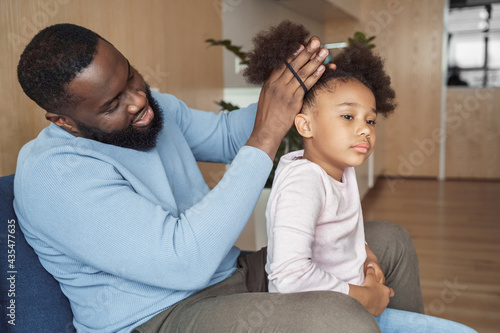 African american father brushing making hairstyle for his young daughter