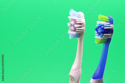 Old toothbrush and new toothbrush on green background, space for text