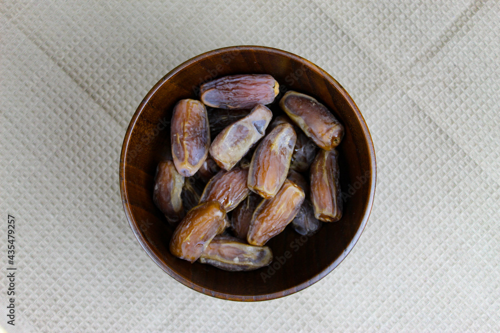 Wooden bowl with dates on the table. Fruit on a wooden tray. Fruit dates. Walnut kernels. The concept of Ramadan. Wooden bowl with dates on the table. Fruit on a wooden tray. Fruit dates. Walnut kernels. The concept of Ramadan.