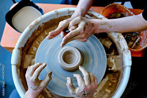 Beautiful female and teenage hands over the potter's wheel. Sculpt from clay in a pottery workshop. Traditional pottery craft. Ceramics workshop concept