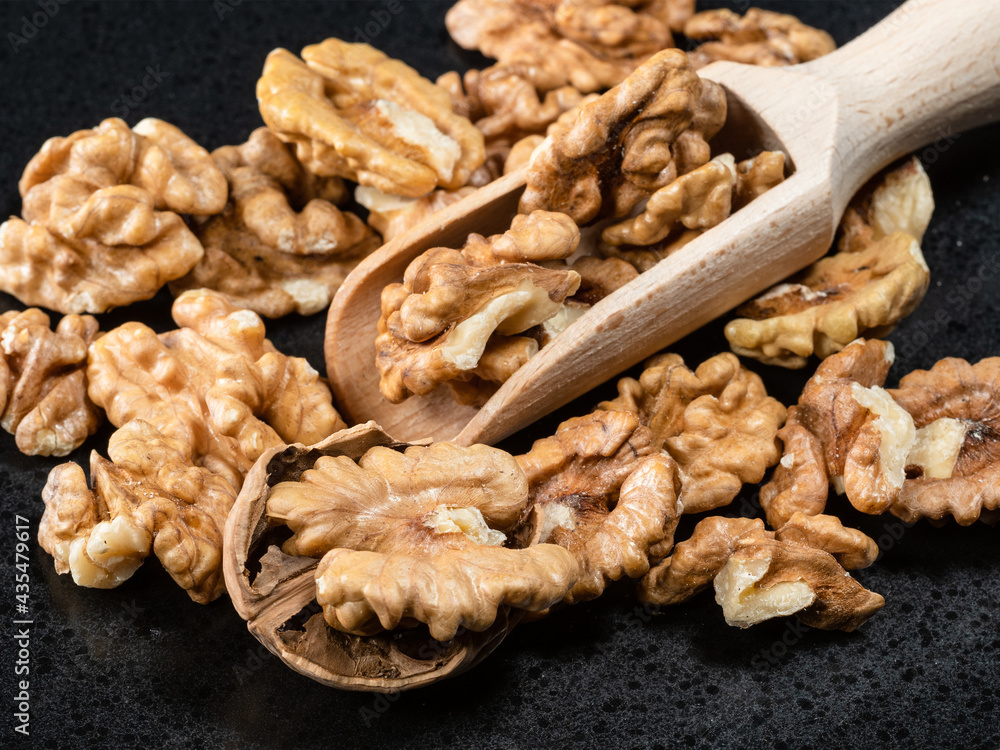 Obraz premium wooden scoop in heap of peeled walnuts closeup