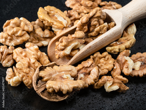 wooden scoop in heap of peeled walnuts closeup