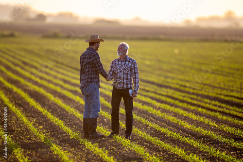 Two men shaking hands in corn field reaching agreement. photo