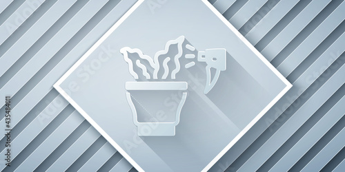 Paper cut Spraying a house plant with a spray gun icon isolated on grey background. Moistening of foliage. Care for home flowers. Paper art style. Vector