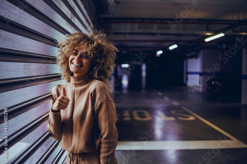 Принти на полотні Smiling mixed race rap girl leaning on garage door and showing thumbs up