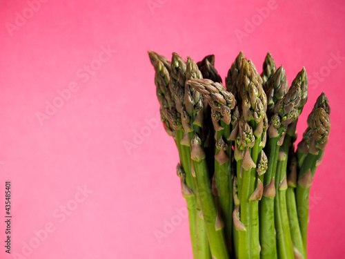 right green asparagus stands on a pink background side view. raw vegetable. veganism