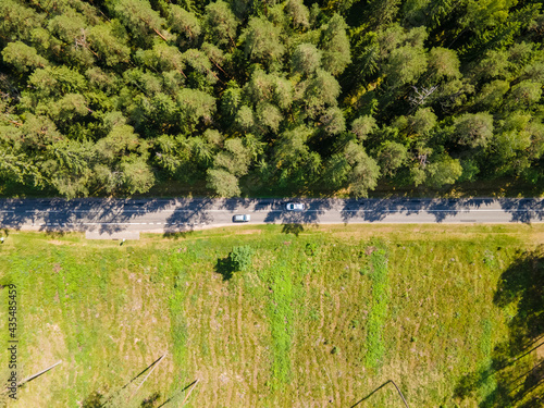 Aerial view of a rural landscape of woodland and grassland separated by a road in the middle