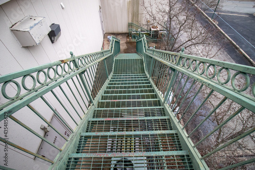 Green metal staircase behind shopping center building on cloudy day in winter