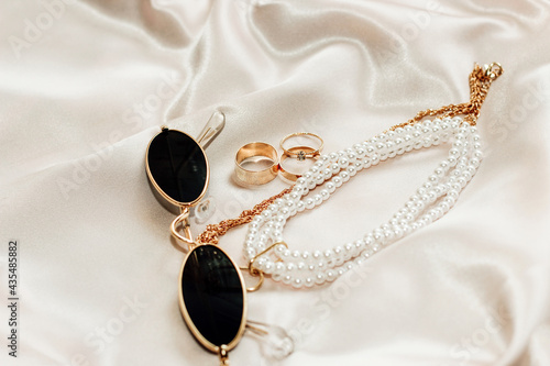 Flatley with gold jewelry and pearls on a silk background, glasses in the frame photo