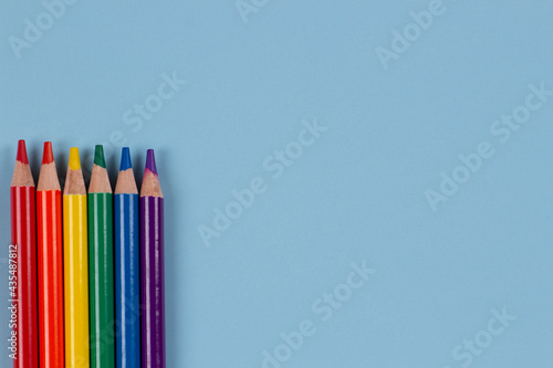 Colored pencils with rainbow colors of LGBT gay pride flag arranged on light blue background. Top view