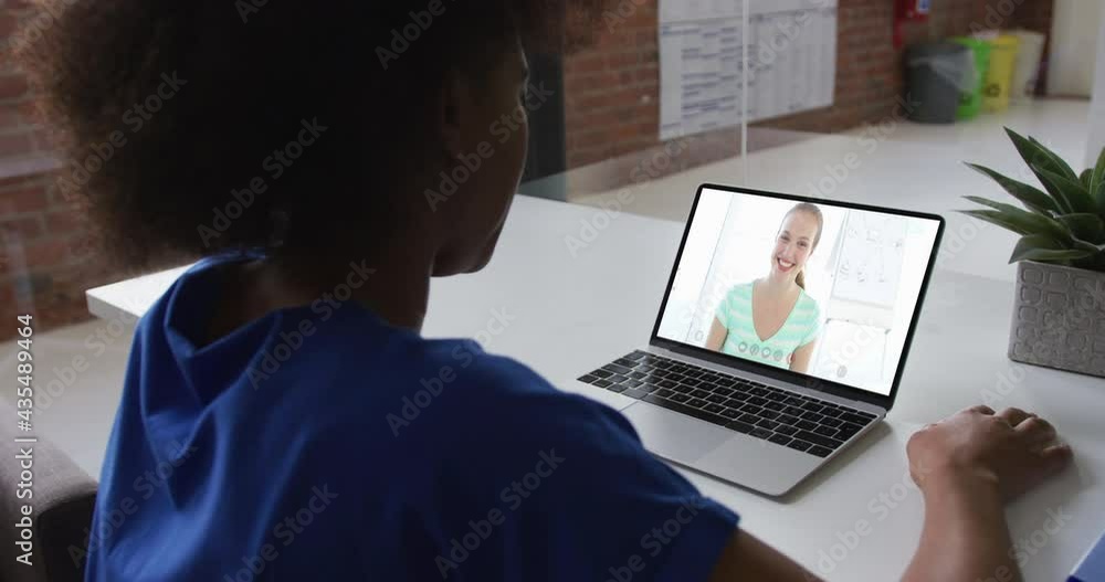 African american businesswoman sitting at desk using laptop having video call with female colleague African american businesswoman sitting at desk using laptop having video call with female colleague