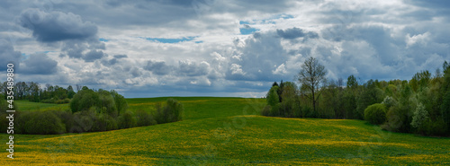 broken summer clouds over countryside fields and meadows in summer with yellow flowers
