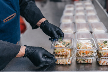 Food in disposable dishes ready for delivery. The chef prepares food in the restaurant and packs it in disposable lunch boxes.