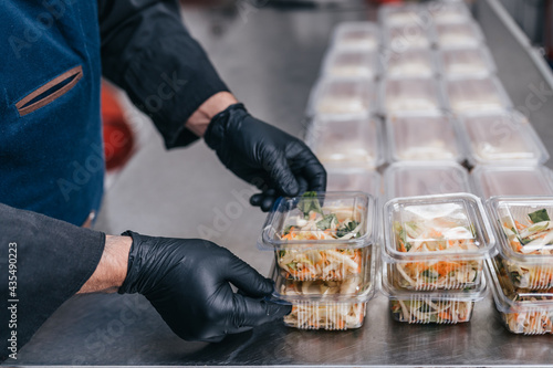 Food in disposable dishes ready for delivery. The chef prepares food in the restaurant and packs it in disposable lunch boxes. photo