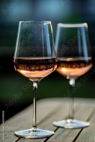 Glasses made of transparent glass with rose wine on the table, dinner