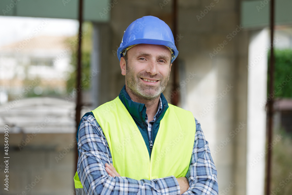 happy young man builder in helmet standing with arms crossed happy young man builder in helmet standing with arms crossed