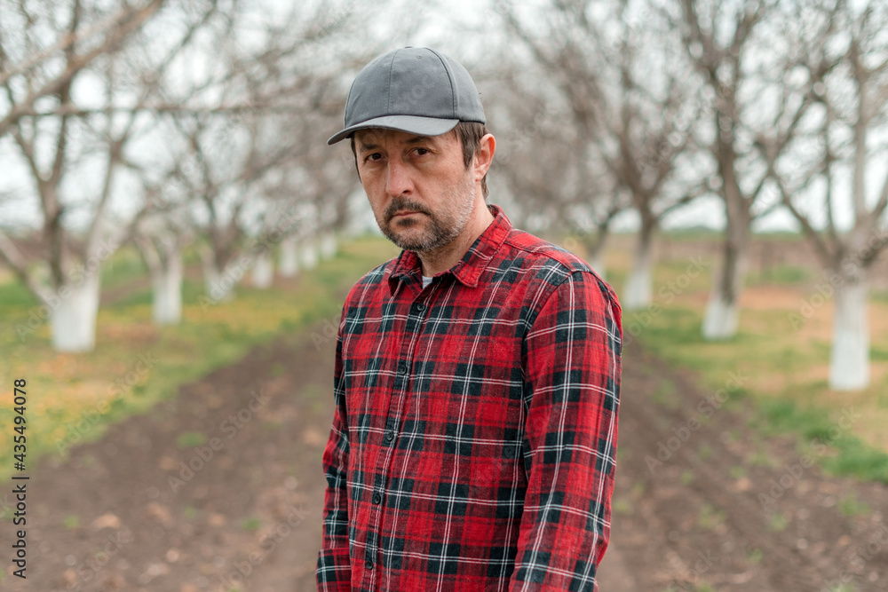 Portrait of handsome confident farmer in walnut fruit orchard looking at camera Portrait of handsome confident farmer in walnut fruit orchard looking at camera