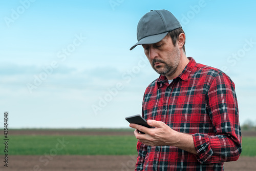 Farmer using smart phone app for crops management out in the field