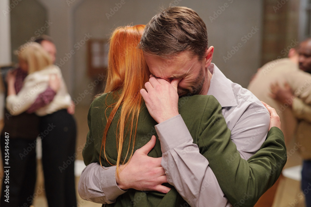 Crying man being supported by female in green suit during psychological session Crying man being supported by female in green suit during psychological session