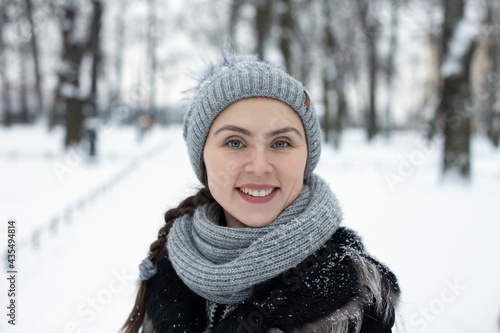 Beautiful woman with long hair in a gray hat on the background of a winter park