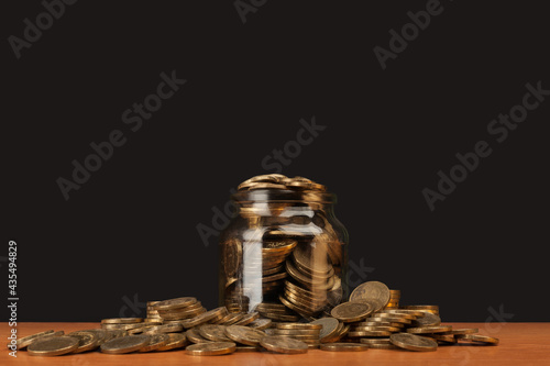 scattered money in a glass jar on the table.